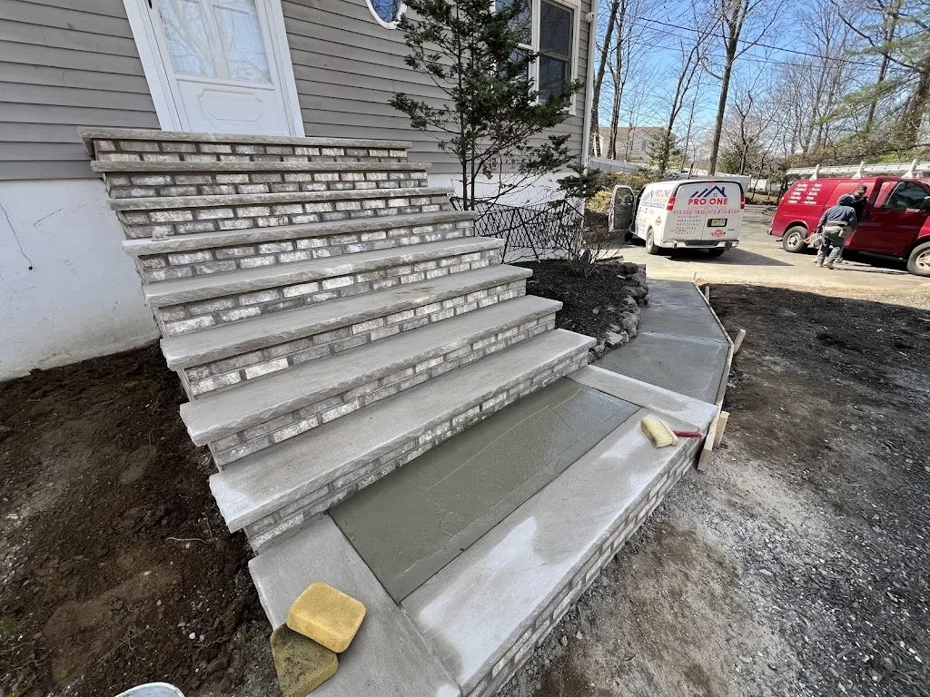 Brick steps with bluestone treads beside a freshly poured concrete walkway