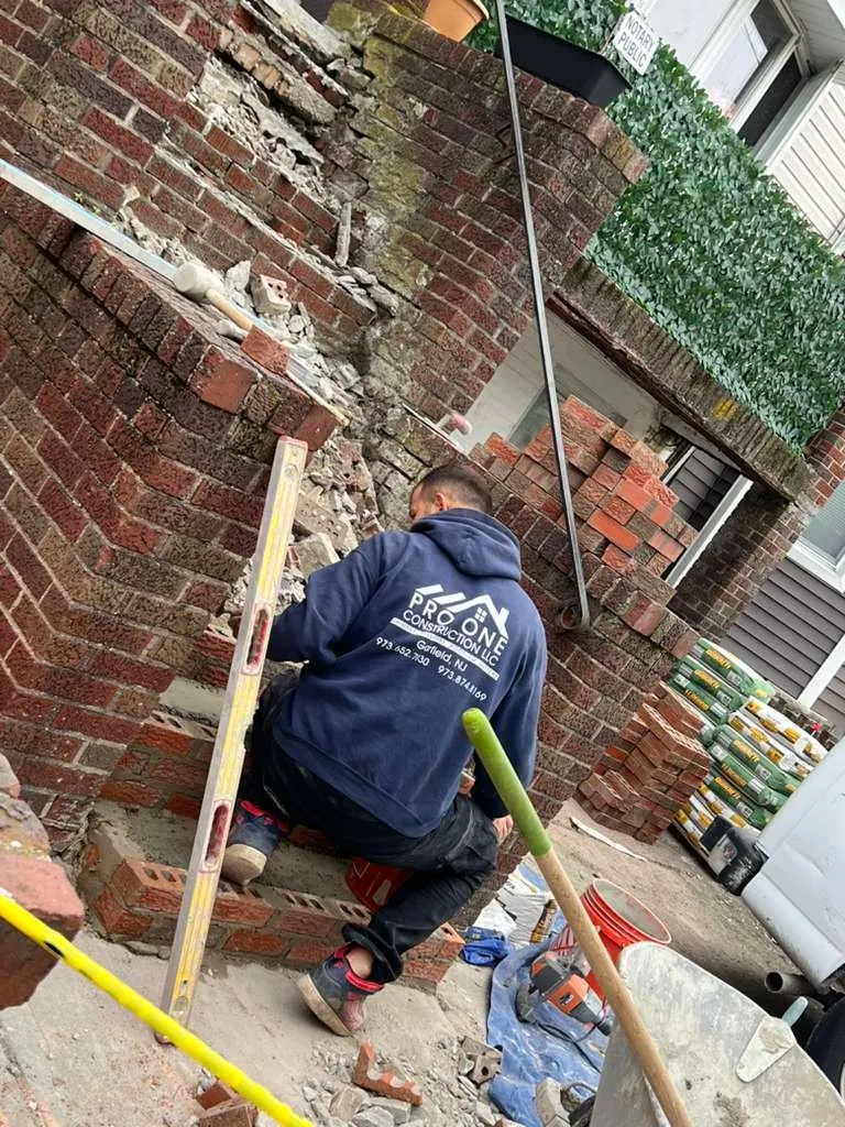 Pro One mason rebuilding a brick pillar beside a city stoop