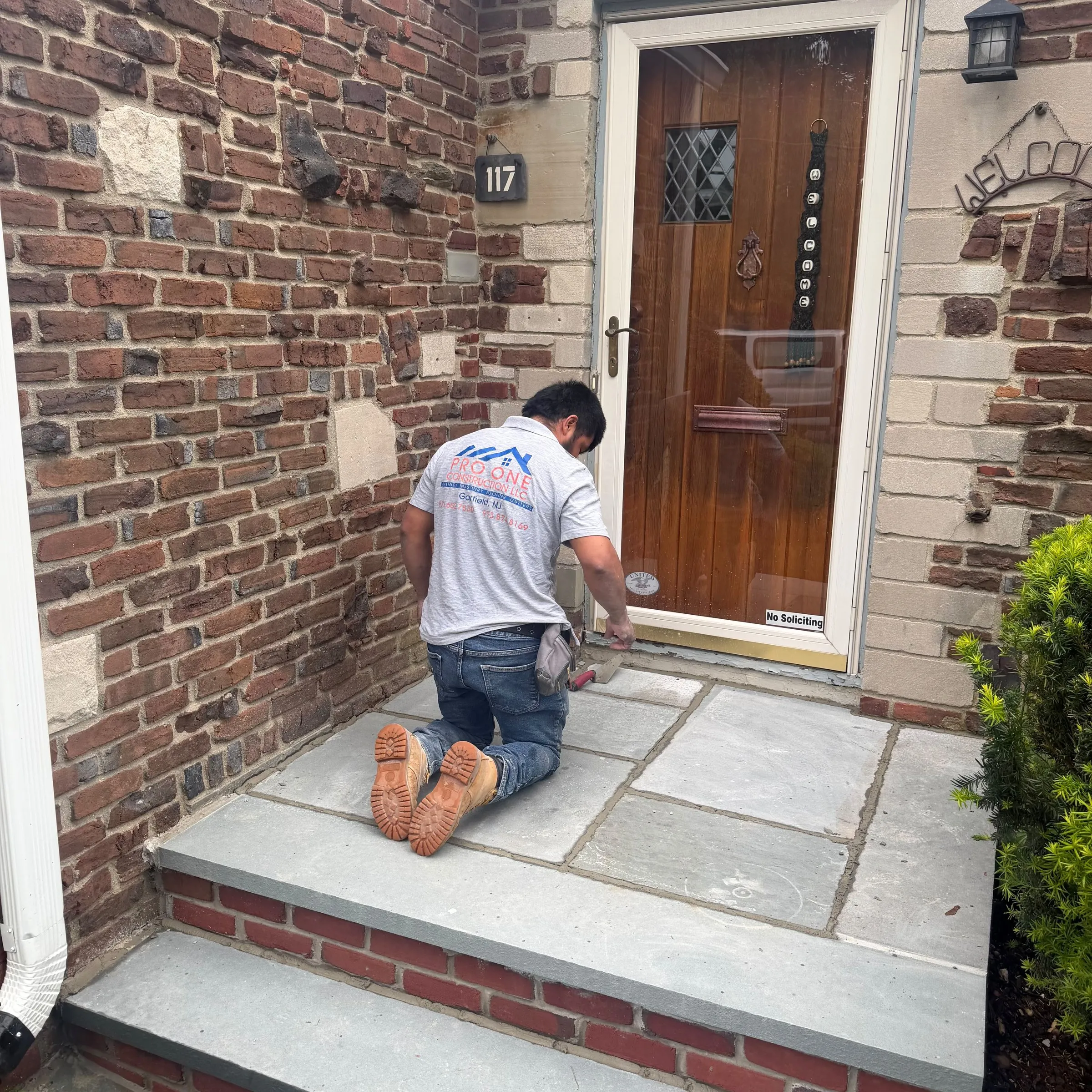 Pro One mason setting bluestone on a front landing at a brick home
